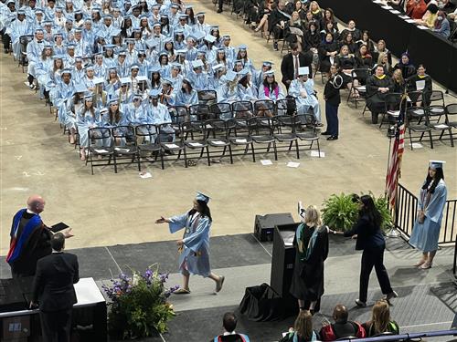 james clemens student walking across stage for diploma with students in background